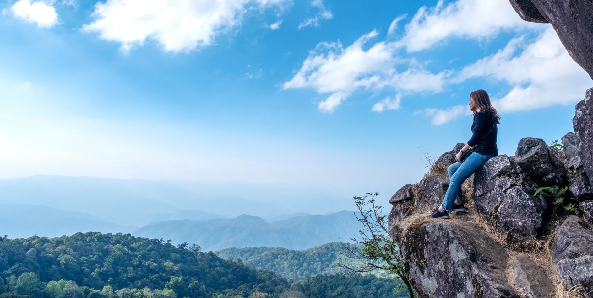 Woman sitting on a rock overlooking mountains