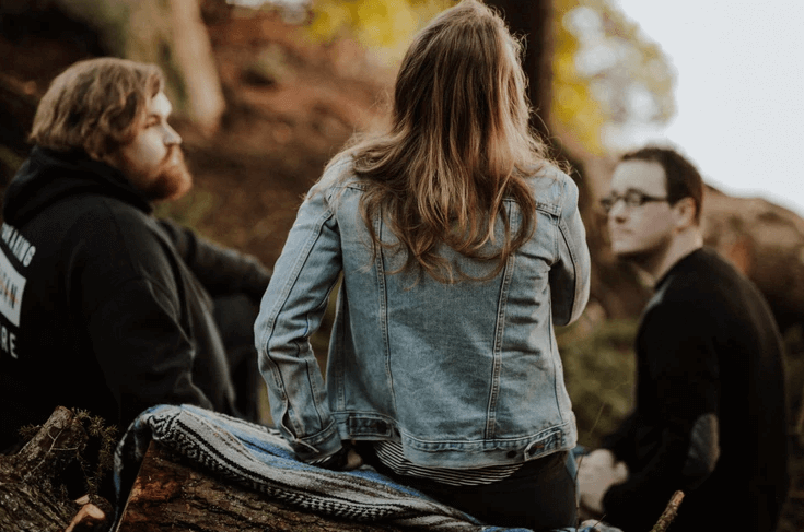 Three people sitting in the woods