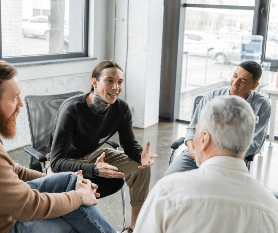 Four individuals seated in a circle during a counseling session, engaged in discussion.