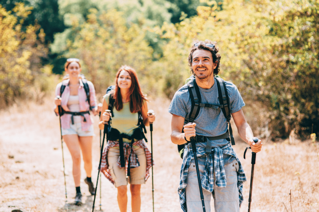 A group of friends hiking on a sunny trail, highlighting the positive impact of physical activity on building confidence and resilience during addiction recovery.