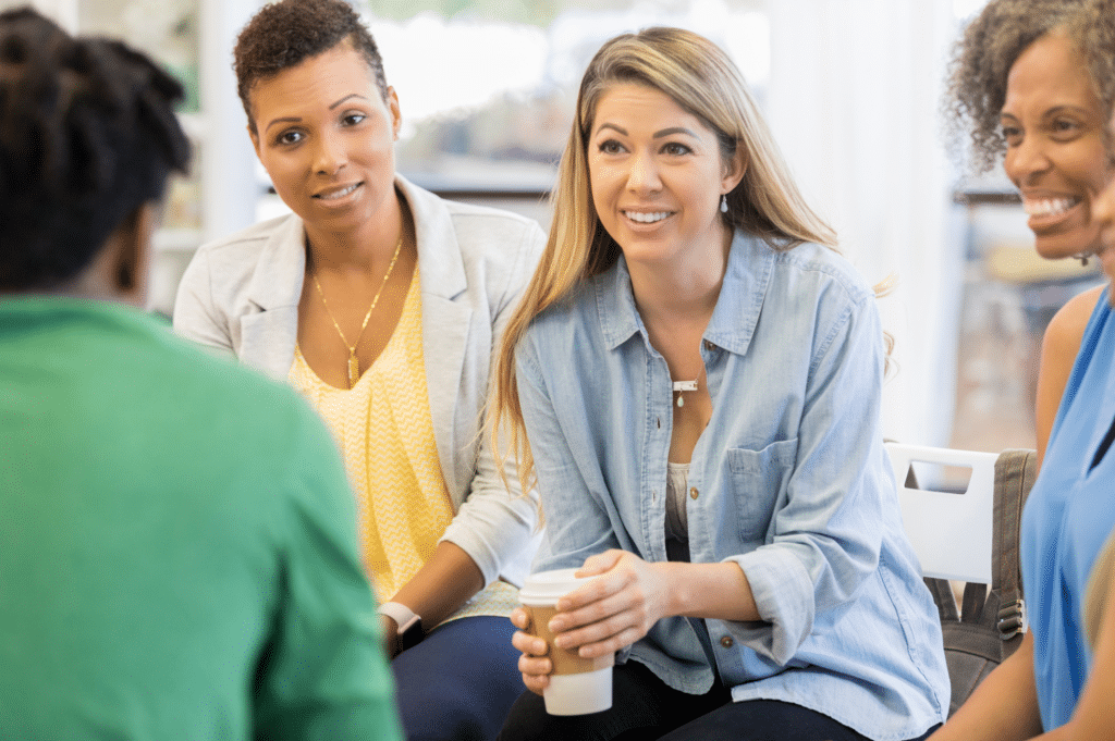 A group of individuals engaging in a positive and supportive discussion, illustrating the enhancement of self-efficacy through a strong support network, essential for fostering confidence and motivation in addiction recovery.