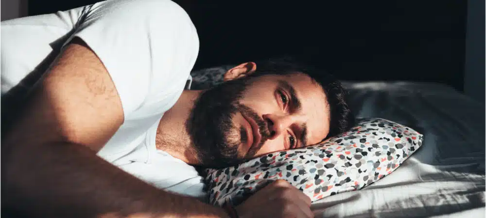 Sad man laying on bed looking into distance