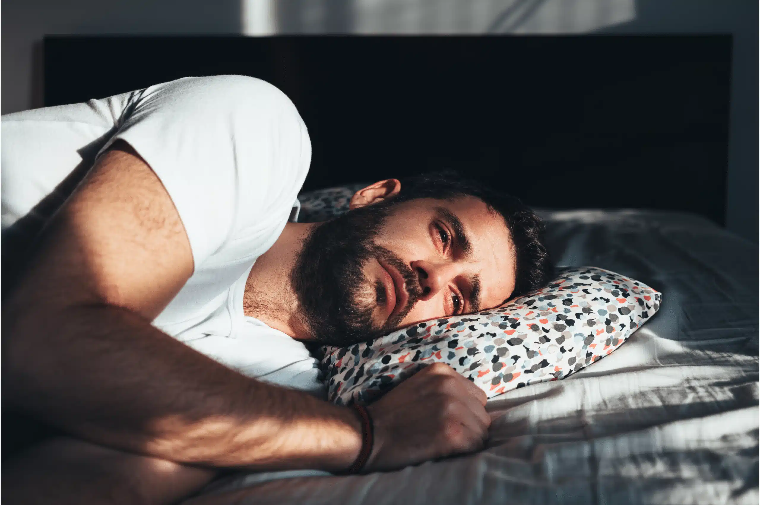 Sad man laying on bed looking into distance